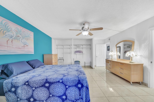 bedroom featuring ceiling fan, light tile patterned flooring, and a textured ceiling