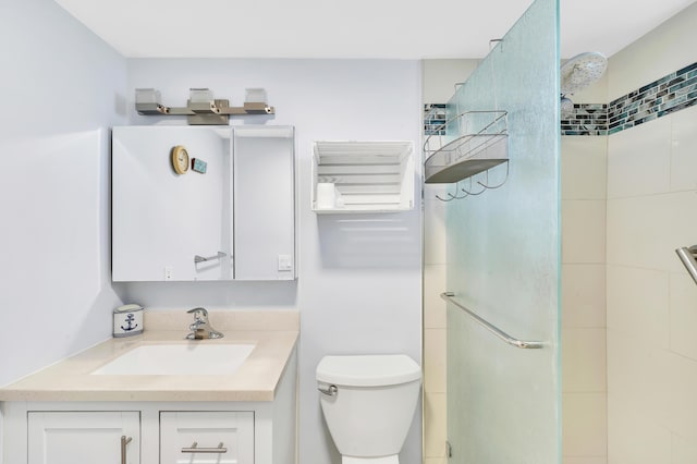 bathroom with tiled shower, vanity, and toilet