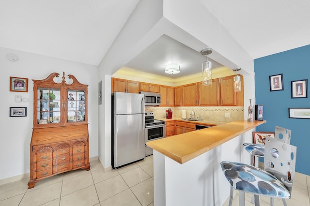 kitchen with pendant lighting, backsplash, sink, appliances with stainless steel finishes, and a breakfast bar area