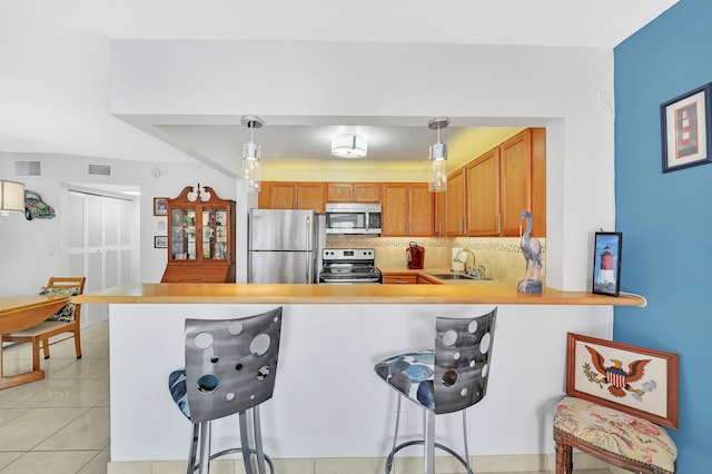 kitchen with a breakfast bar, appliances with stainless steel finishes, pendant lighting, and sink