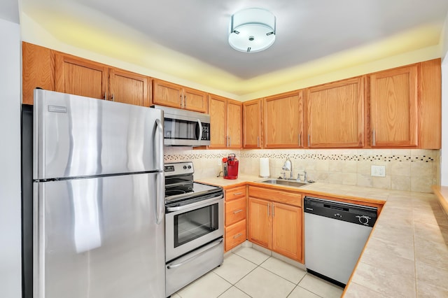 kitchen featuring backsplash, sink, tile counters, light tile patterned flooring, and stainless steel appliances