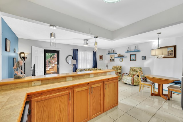 kitchen with tile counters, light tile patterned floors, and pendant lighting