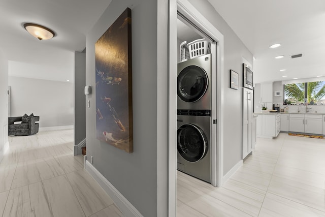 laundry area featuring stacked washing maching and dryer and sink