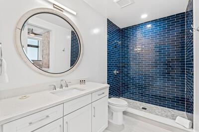 bathroom with a tile shower, vanity, and toilet