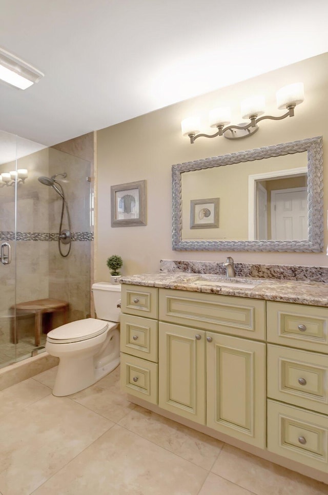 bathroom with tile patterned floors, vanity, toilet, and a shower with shower door