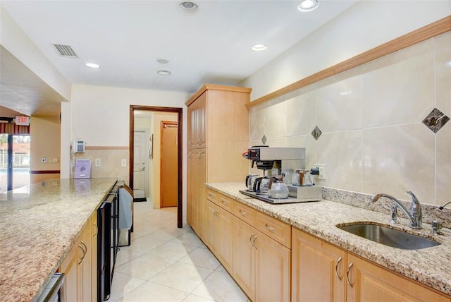 kitchen featuring light brown cabinets, light stone counters, light tile patterned floors, and sink