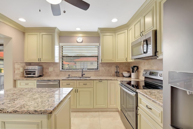 kitchen featuring light stone countertops, sink, appliances with stainless steel finishes, and cream cabinets