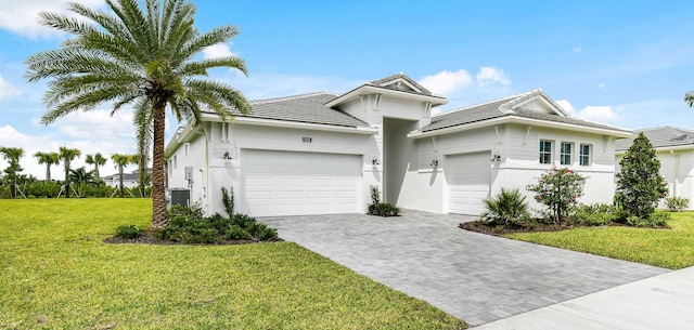 single story home featuring an attached garage, decorative driveway, a front lawn, and stucco siding