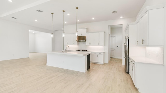 kitchen featuring white cabinets, decorative light fixtures, light wood-type flooring, and a kitchen island with sink