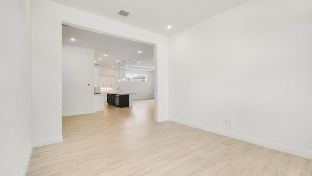 unfurnished room featuring light wood-type flooring and sink