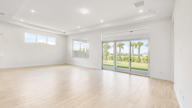 unfurnished room featuring a tray ceiling and light wood-type flooring