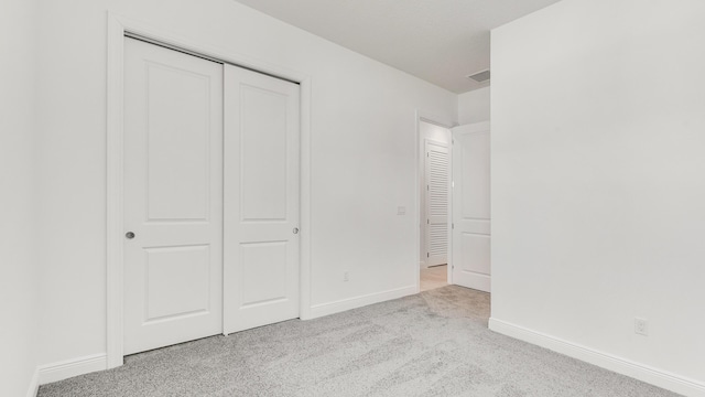 unfurnished bedroom with light carpet and a closet