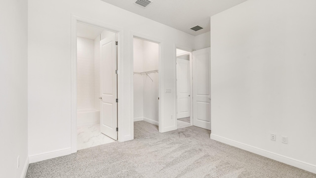 unfurnished bedroom featuring light colored carpet, a spacious closet, and a closet