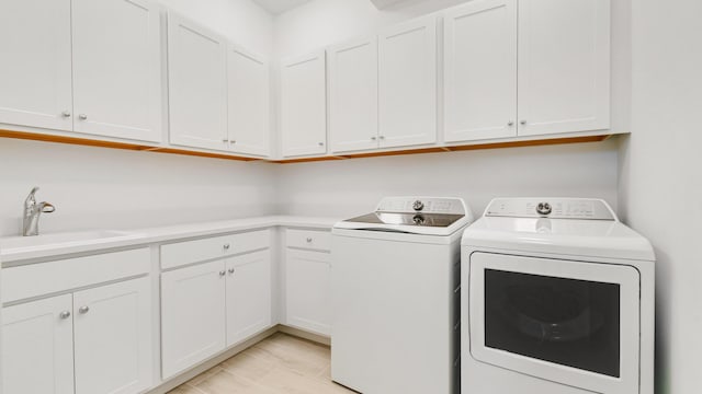 laundry room with washing machine and dryer, sink, and cabinets