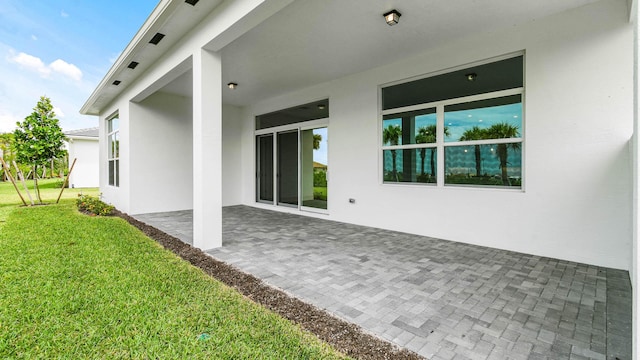 back of property with a yard, a patio area, and stucco siding