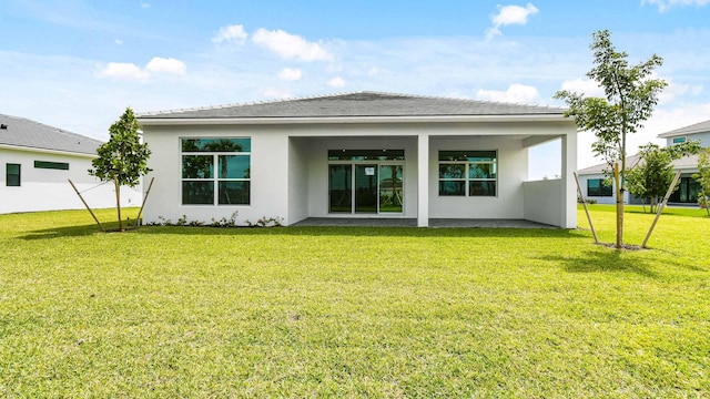 back of property featuring stucco siding and a yard