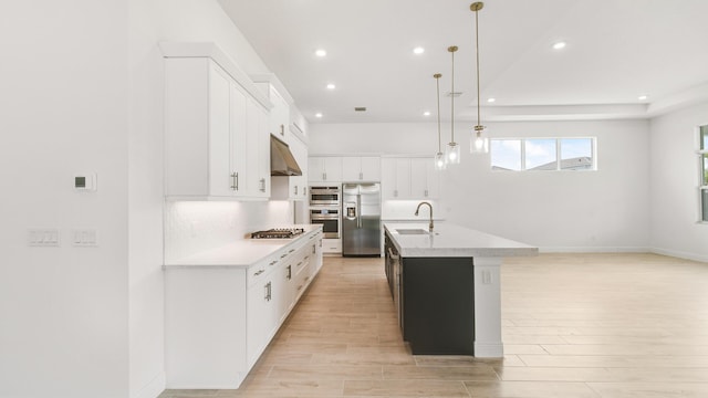 kitchen featuring a center island with sink, white cabinets, sink, decorative light fixtures, and stainless steel appliances