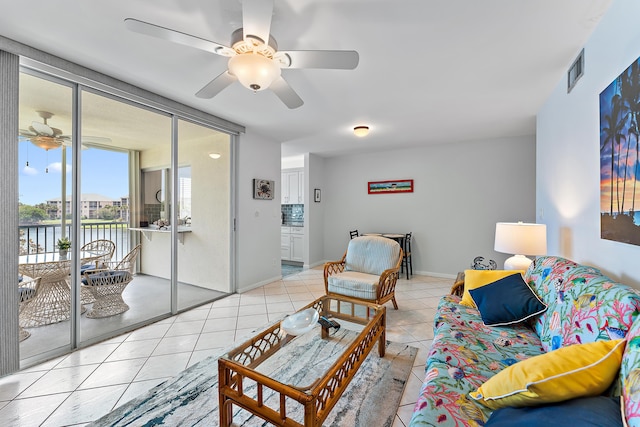 living room with ceiling fan, a water view, and light tile patterned floors