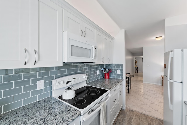 kitchen with decorative backsplash, light stone counters, white appliances, light hardwood / wood-style flooring, and white cabinetry