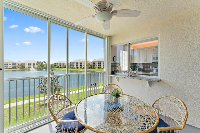 sunroom / solarium with ceiling fan and a water view