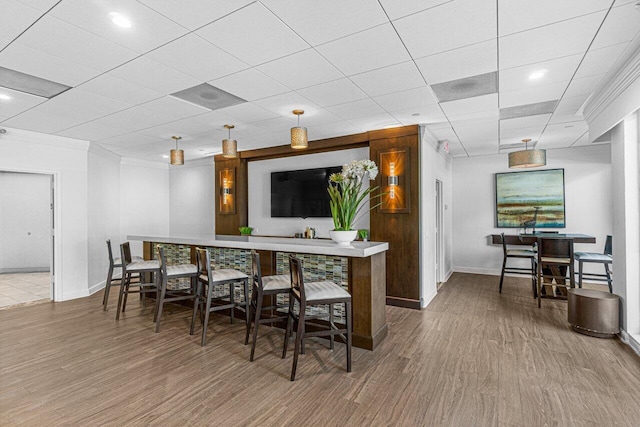 bar featuring crown molding, a paneled ceiling, and wood-type flooring