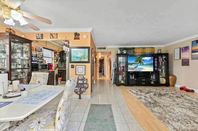 tiled living room with ceiling fan and ornamental molding