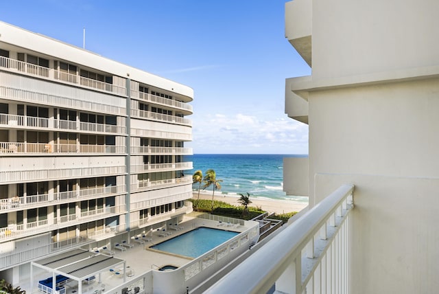 balcony with a water view and a view of the beach