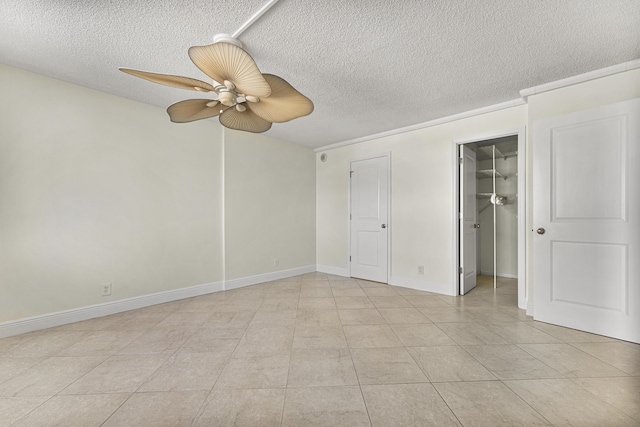 unfurnished bedroom with a walk in closet, ceiling fan, light tile patterned flooring, and a textured ceiling