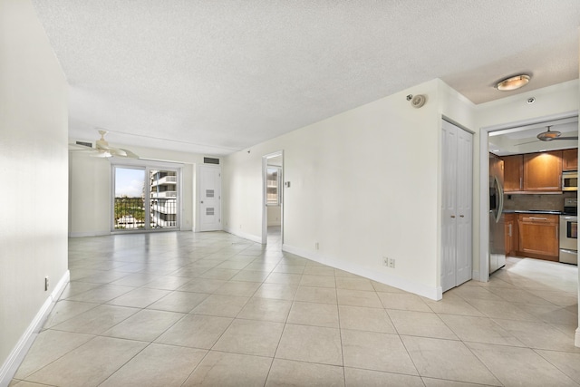 spare room with ceiling fan, light tile patterned floors, and a textured ceiling