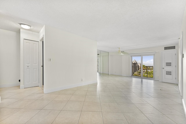 empty room with a textured ceiling, ceiling fan, and light tile patterned flooring