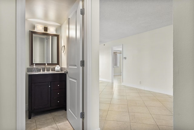 interior space with a textured ceiling, sink, and light tile patterned flooring