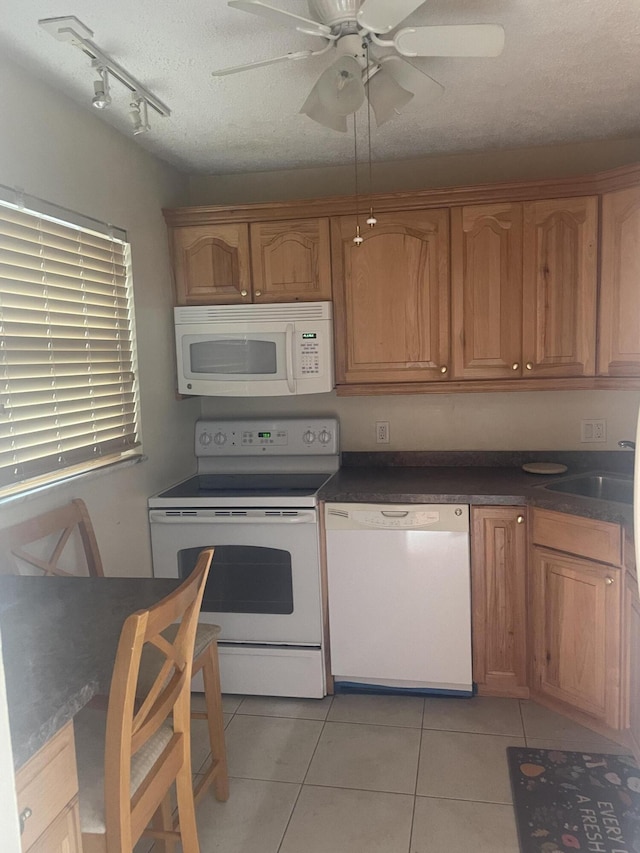 kitchen featuring white appliances, sink, ceiling fan, light tile patterned floors, and a textured ceiling