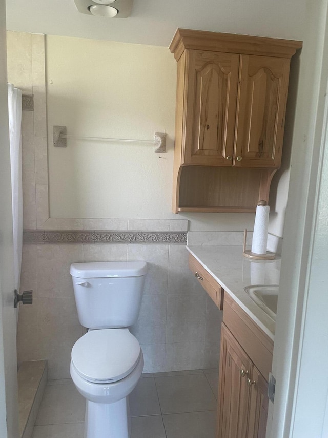 bathroom with tile patterned flooring, vanity, toilet, and tile walls