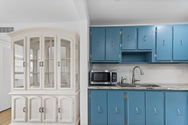 kitchen with blue cabinetry, light hardwood / wood-style flooring, sink, and tasteful backsplash