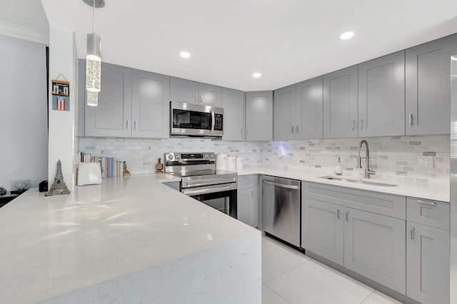 kitchen featuring pendant lighting, gray cabinetry, sink, decorative backsplash, and stainless steel appliances