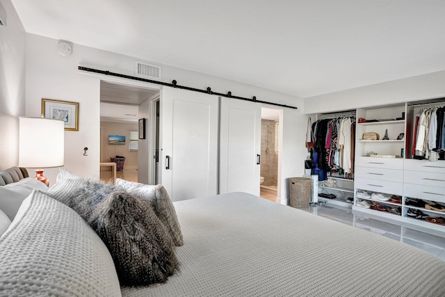 bedroom featuring tile patterned flooring, a barn door, connected bathroom, and a closet