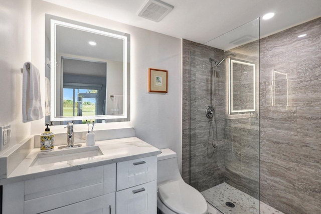 bathroom featuring a tile shower, vanity, and toilet