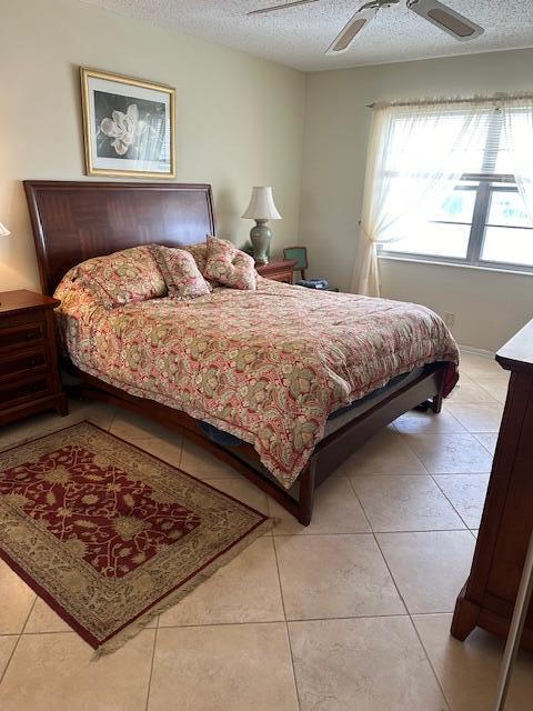 bedroom with ceiling fan, light tile patterned floors, and a textured ceiling