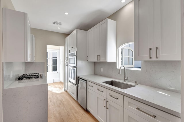 kitchen featuring sink, light stone countertops, white cabinetry, and stainless steel appliances