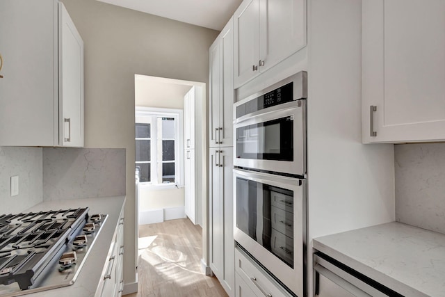 kitchen featuring white cabinetry, light hardwood / wood-style flooring, light stone counters, and appliances with stainless steel finishes