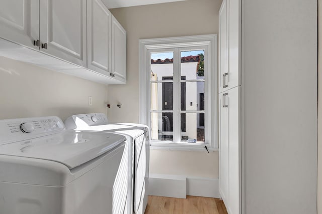 washroom featuring washer and clothes dryer, light hardwood / wood-style flooring, and cabinets