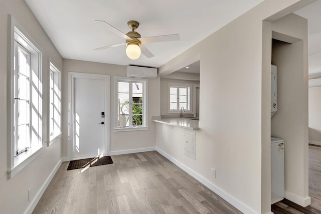 foyer with ceiling fan, sink, light hardwood / wood-style floors, and a wall mounted air conditioner