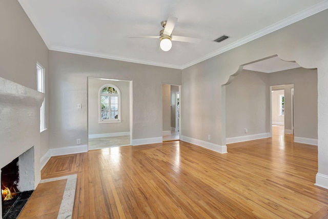 unfurnished living room featuring ceiling fan, ornamental molding, and light wood-type flooring