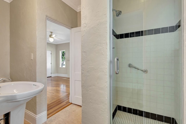 bathroom with ceiling fan, wood-type flooring, a shower with shower door, and ornamental molding