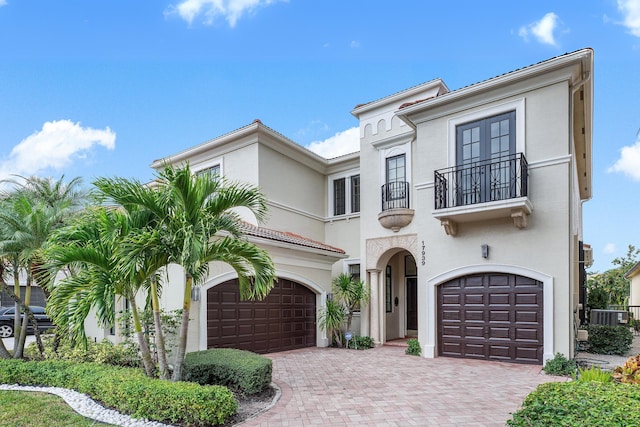 mediterranean / spanish house with a balcony, central AC unit, and a garage