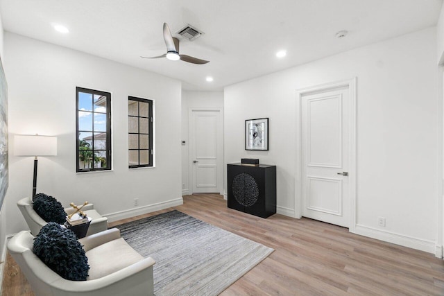 living area with a ceiling fan, visible vents, light wood-style flooring, and baseboards