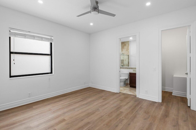 unfurnished bedroom with baseboards, a spacious closet, light wood finished floors, and recessed lighting