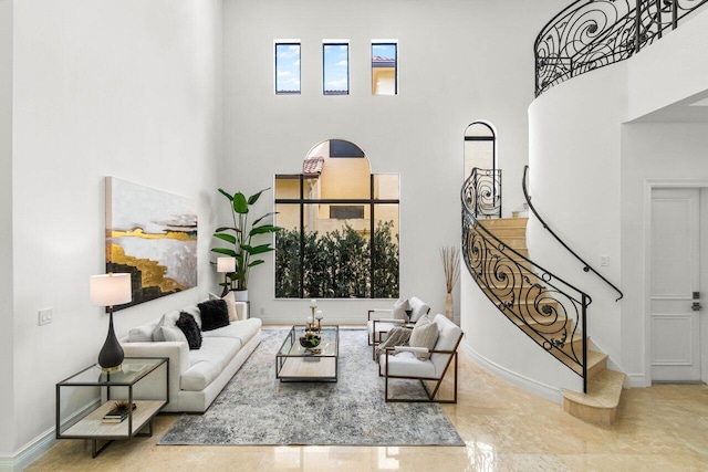 living area with stairs, a high ceiling, and baseboards