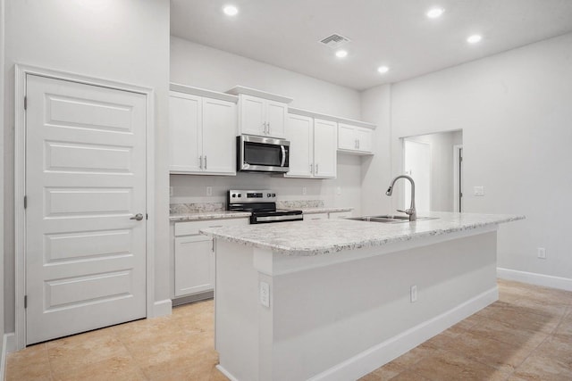 kitchen with appliances with stainless steel finishes, white cabinetry, and a kitchen island with sink