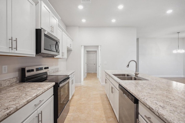 kitchen with decorative light fixtures, stainless steel appliances, white cabinetry, and sink